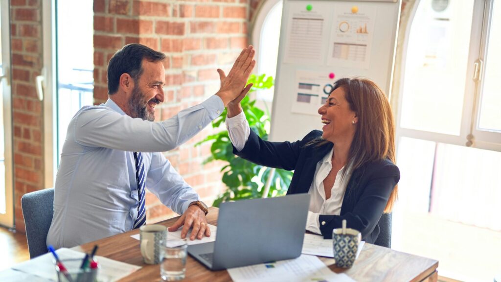 man and woman high-fiving at a desk