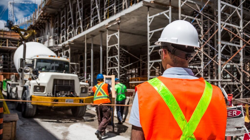Construction worker stands in front of building that's being built